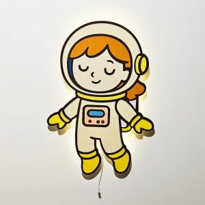 Kız Astronot lambanın ışığı açık; figürün arkasından beyaz duvara yayılan sıcak sarı ışık ve çekme ipi