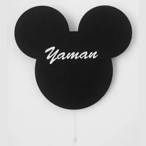 Mickey lambanın siyah modeli ışığı kapalı halde beyaz duvarda; ortada beyaz el yazısıyla örnek isim ve çekme ipi