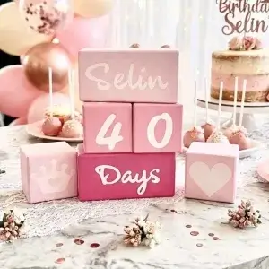 Pembe tonları anı küpü seti doğum günü masasında; pastalar, balonlar ve taç ile kalp simge küpleri arasında