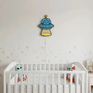 Ufo ahşap gece lambası, ay ve gezegen süslemeli bebek odasında beyaz beşiğin üstünde, ışığı kapalı halde